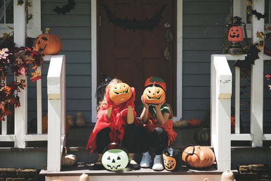 two kids wearing Halloween costumes outside their house